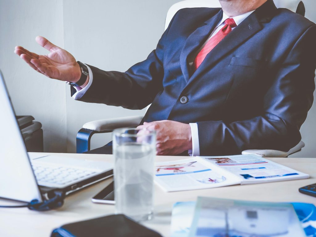 pexels-photo-288477-288477 Professional man gesturing in a business meeting at an office desk, conveying confidence and leadership.